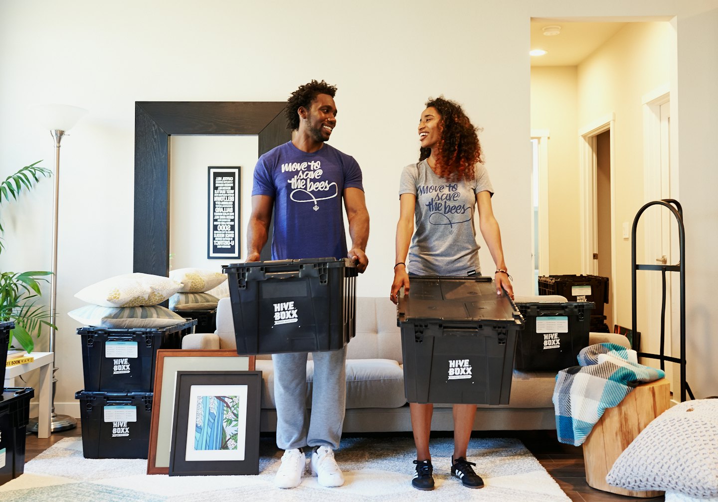 Uomo e donna portano scatoloni Hive Boxx in una nuova casa.