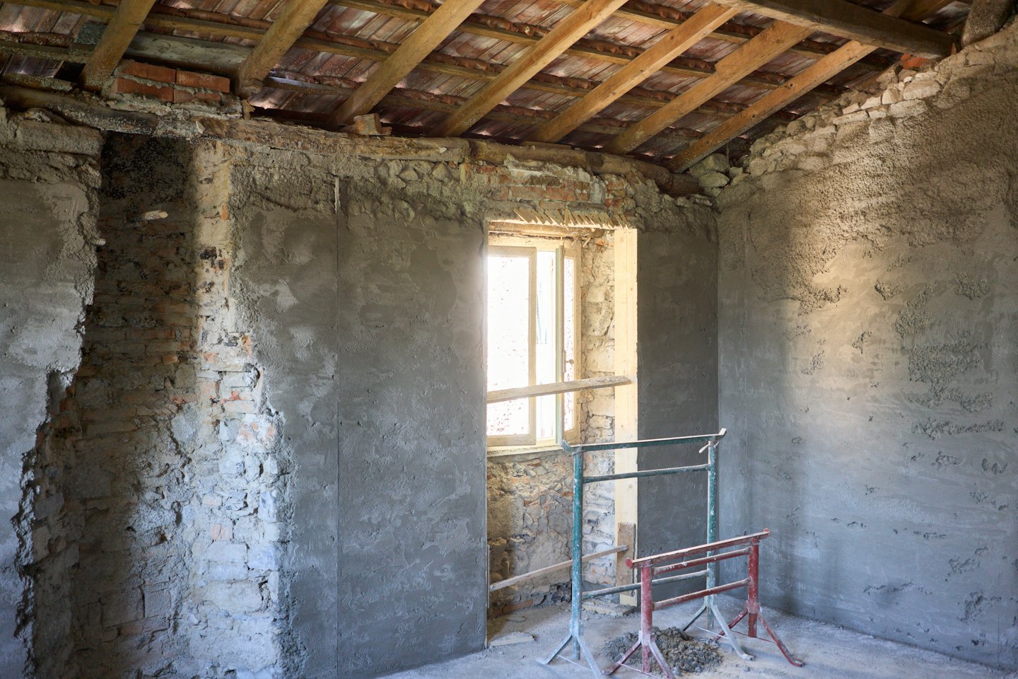 Ristrutturazione di una stanza con muri in mattoni a vista e ponteggi in legno.